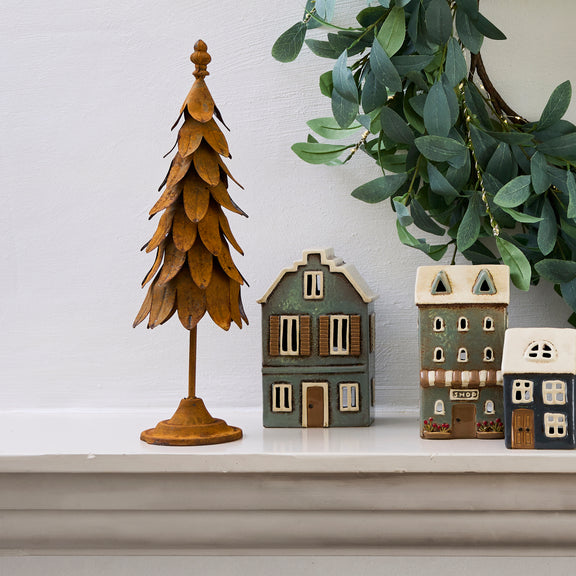 Ceramic tealight house glowing with candle inside, styled on a festive mantle
