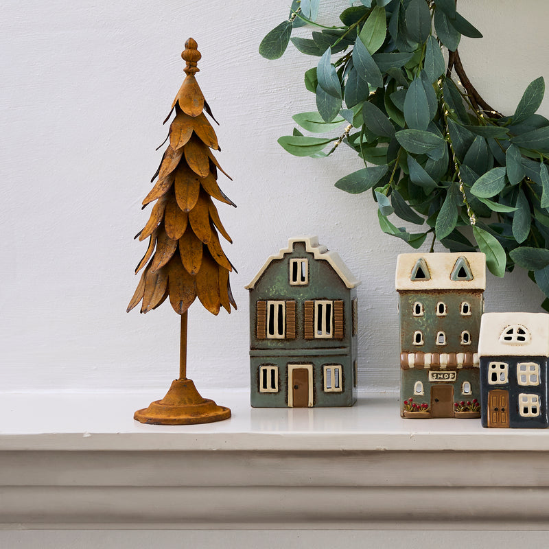 Ceramic tealight house glowing with candle inside, styled on a festive mantle