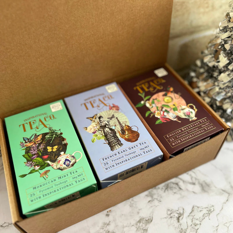 Three tea boxes with colorful designs on a marble surface