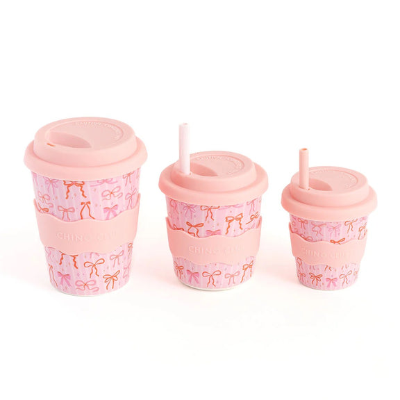 Set of three pink cups with bow patterns on a white background