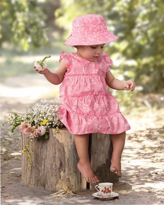 Baby wearing Toshi Acacia Scarlet dress with A-line shape and ruffled sleeves.