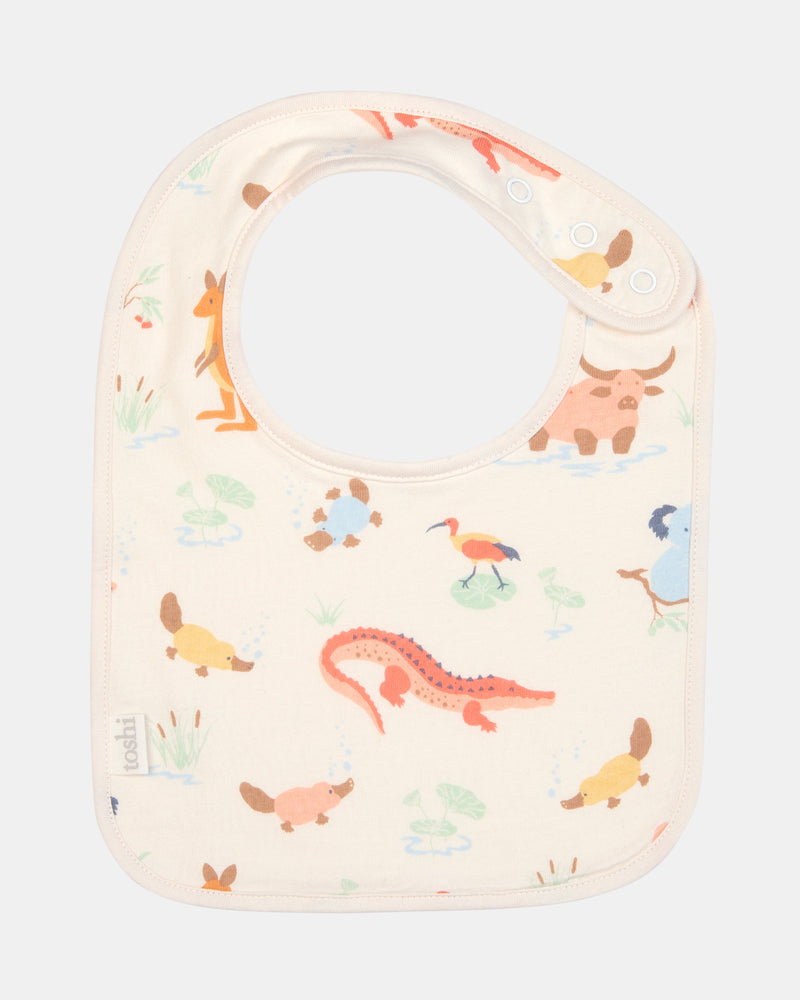 Toshi Baby Bib Down Under Kakadu Dawn flat-lay showing front cotton print and press studs.