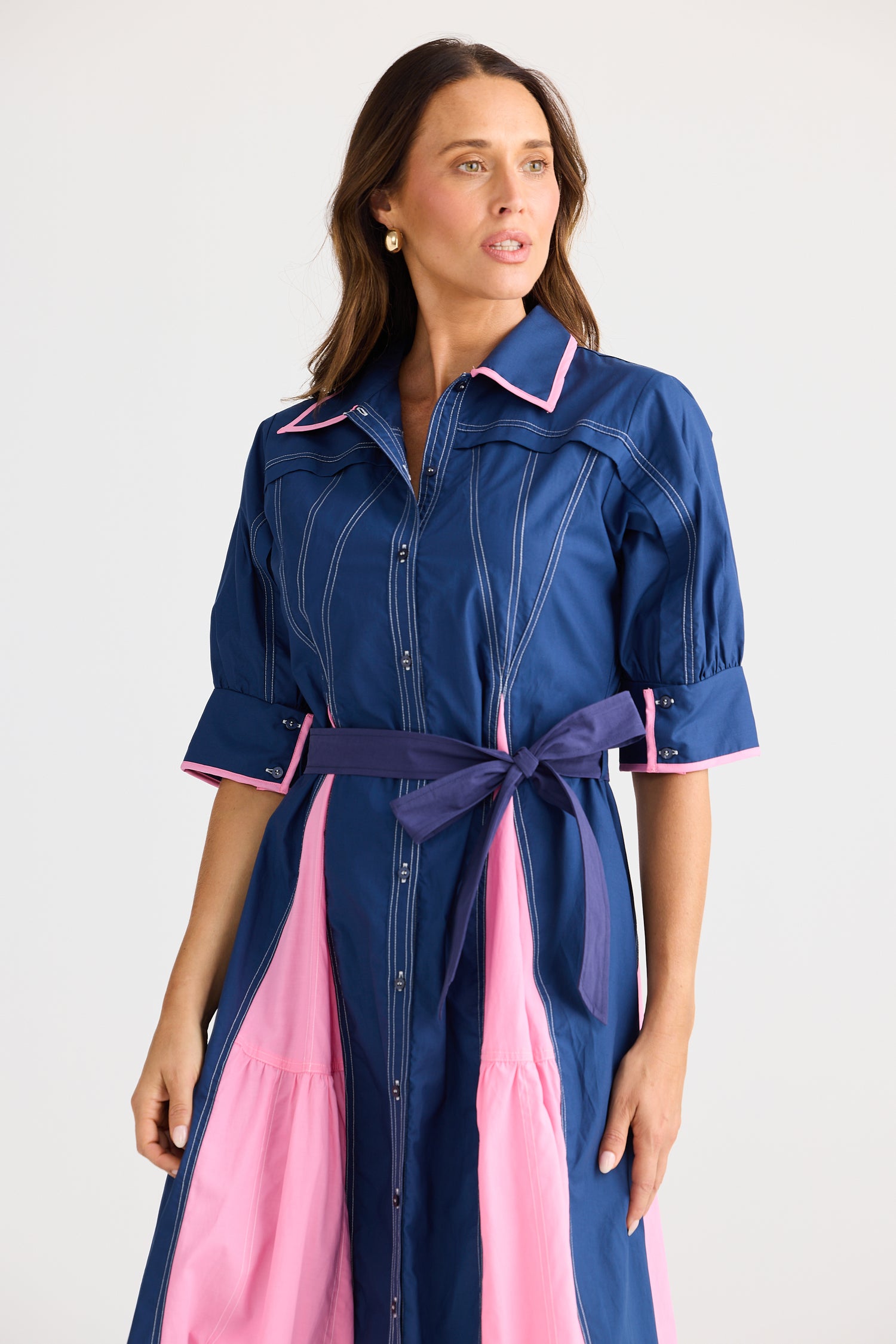 Woman wearing a blue and pink dress with a belt on a white background