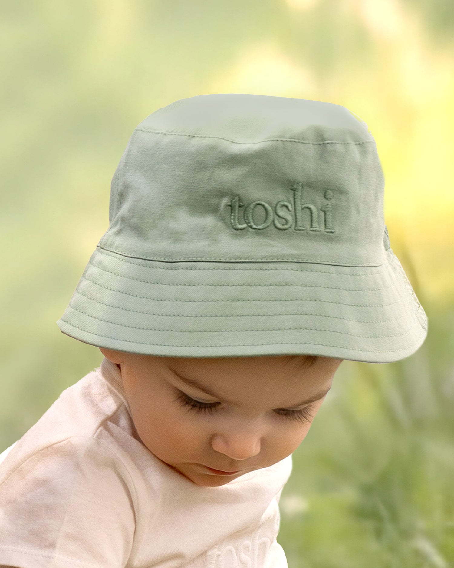 Outdoor scene of child playing in Toshi Teal bucket hat under sunlight.