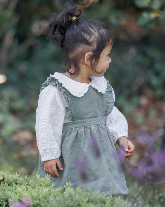 Child in a green dress with white collar standing among greenery and purple flowers - Toshi Baby Blouse Peter Pan Cream