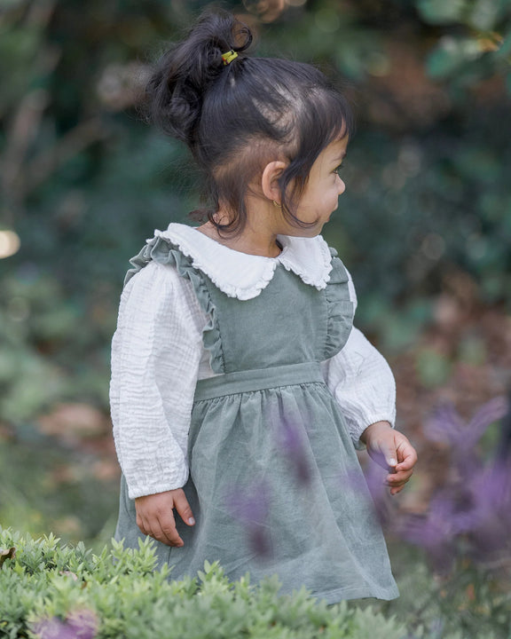 Child in a green dress with white collar standing among greenery and purple flowers - Toshi Baby Blouse Peter Pan Cream