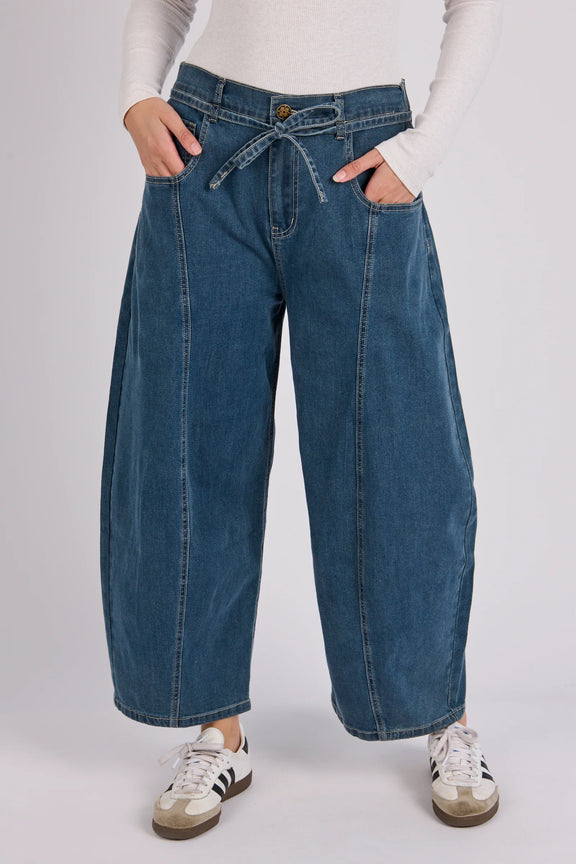 Women's mid blue wash barrel leg jeans with cropped length, tie waist detail and curved leg silhouette.