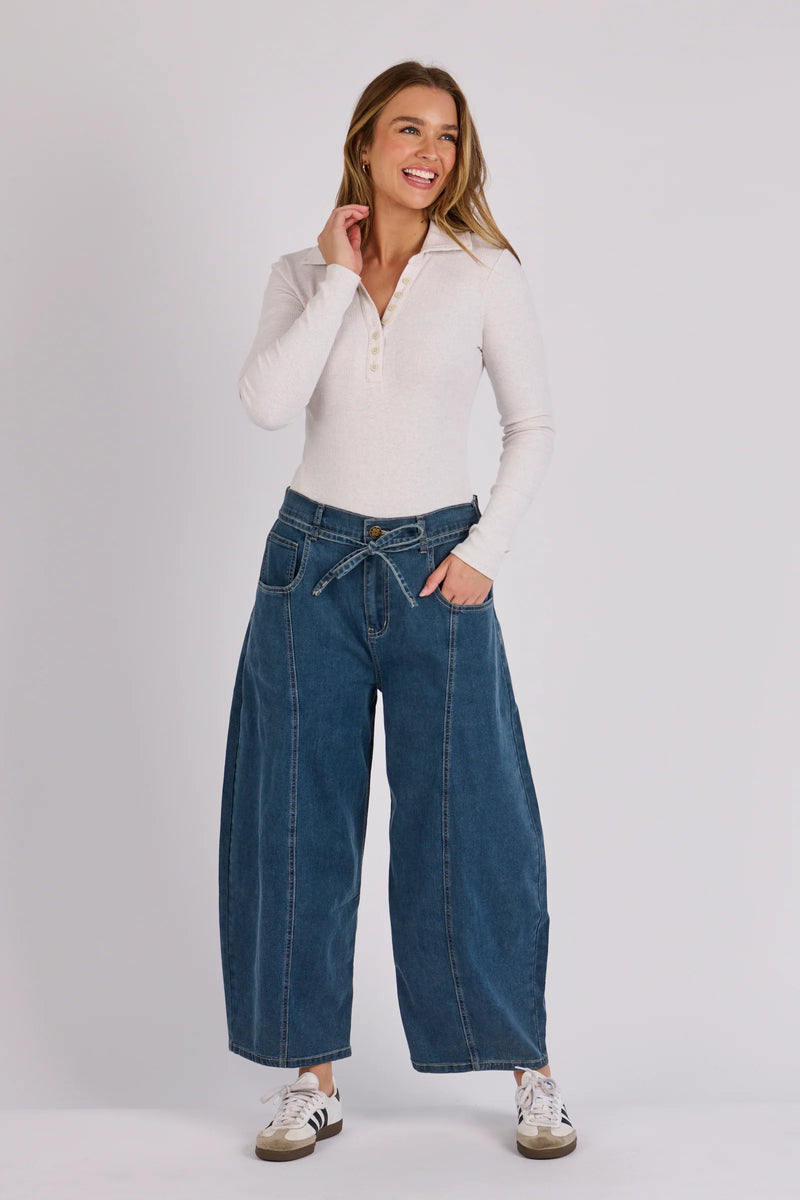 Mid blue barrel leg jeans with curved shape, zip and button closure, and classic denim pocket styling.