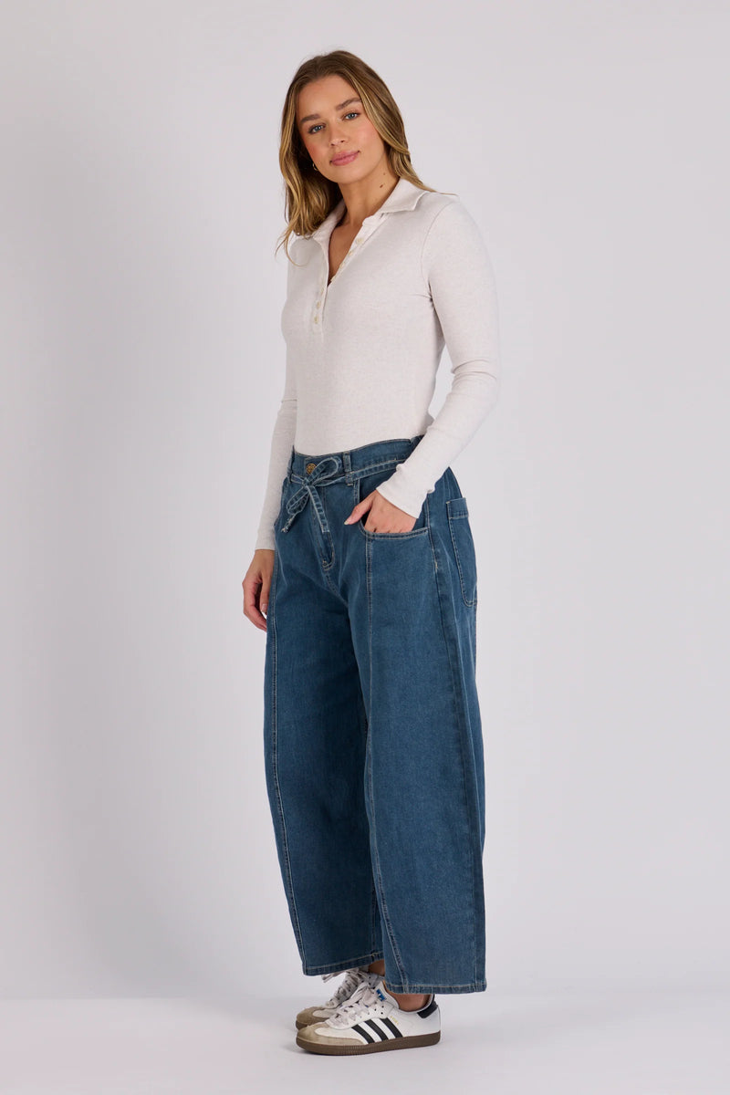 Mid-rise women's barrel leg jeans in stretch denim featuring a cropped length and front tie waist.