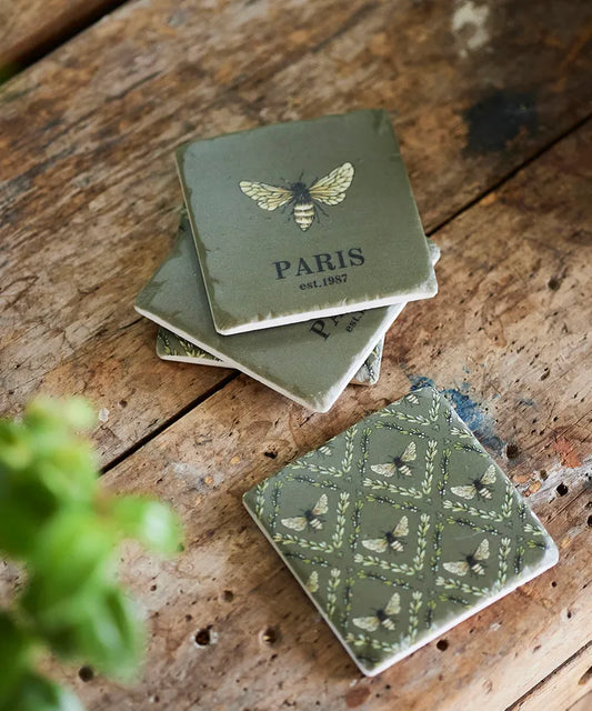 Green coasters with bee design and 'Paris' text on a wooden surface