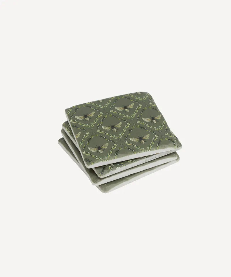 Set of four green patterned coasters on a white background