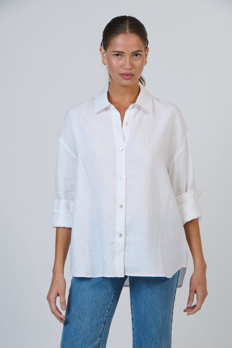 Woman wearing a white shirt and blue jeans against a plain background