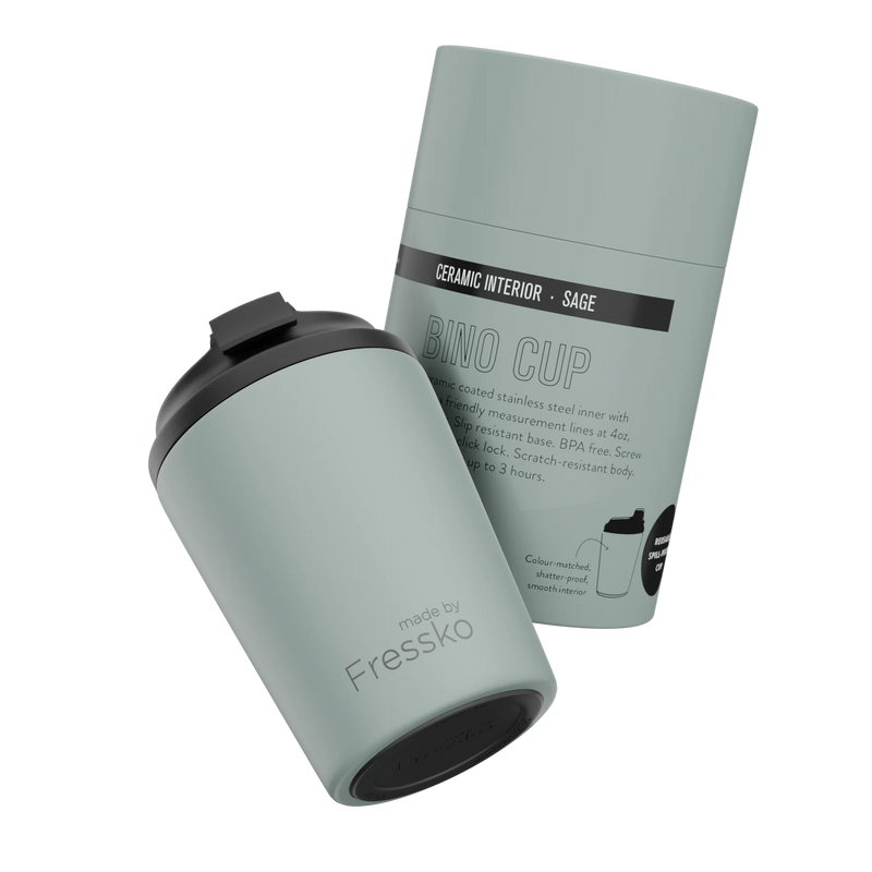 Sage green travel mug with black lid and packaging on a white background