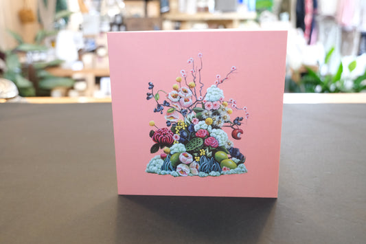 Card with floral design on a pink background, placed on a table. Red Flags Ninni Card.