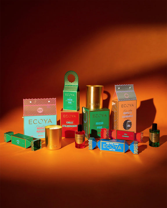 Collection of Ecoya products including boxes and candles on an orange background - Holiday collection