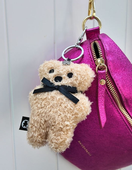 Teddy bear keychain attached to a pink bag with a white background