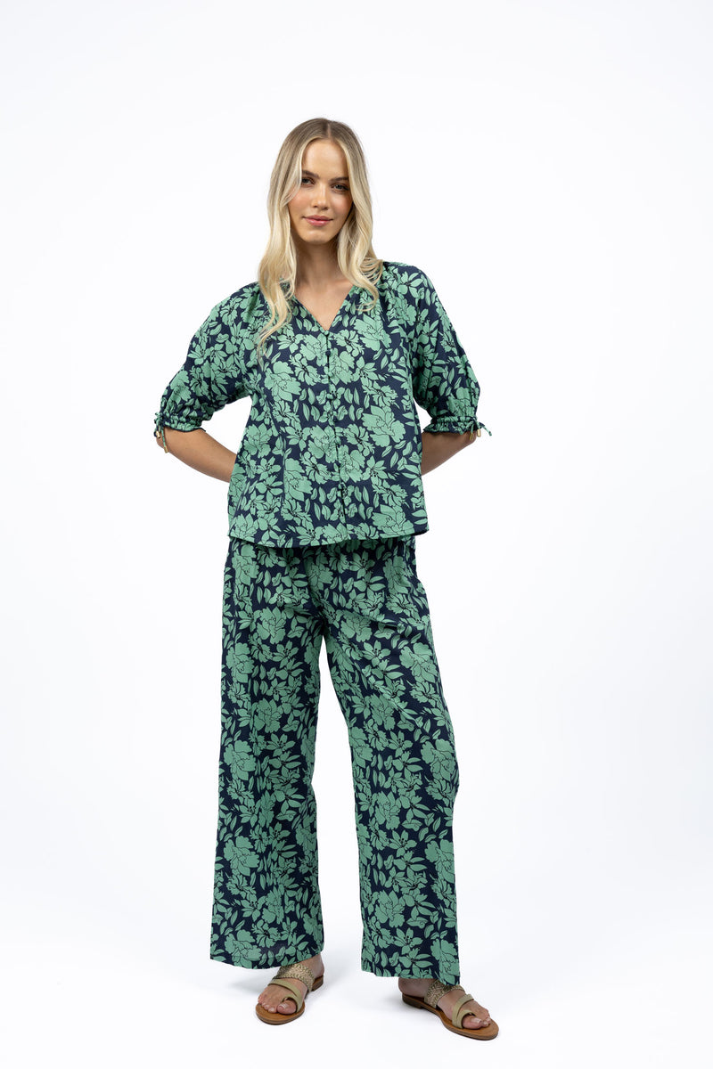 Woman wearing Humidity Fleur Pants in floral cotton print, wide-leg style.