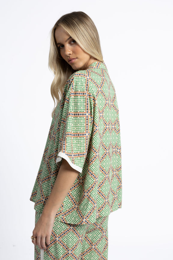 Woman wearing a green patterned dress on a white background