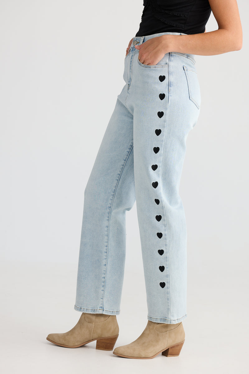 Close-up of embroidered heart detailing on light wash denim