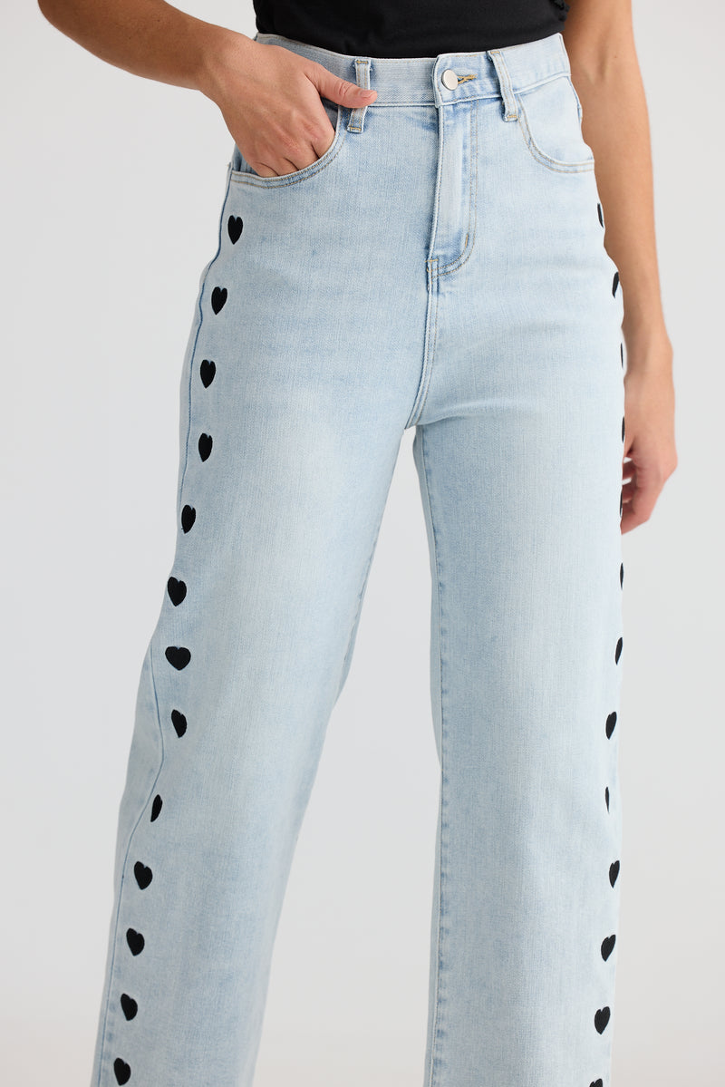 Light blue jeans with black heart patterns on a white background