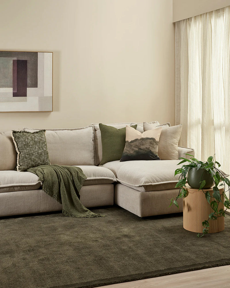 Modern living room with a sectional sofa, decorative pillows, and a plant. Lily Olive Throw