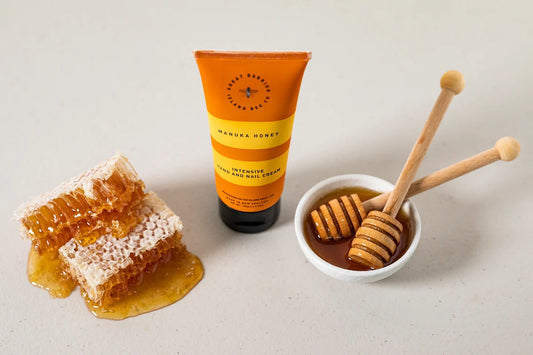 Honeycomb, tube of cream, and honey dipper on a light background