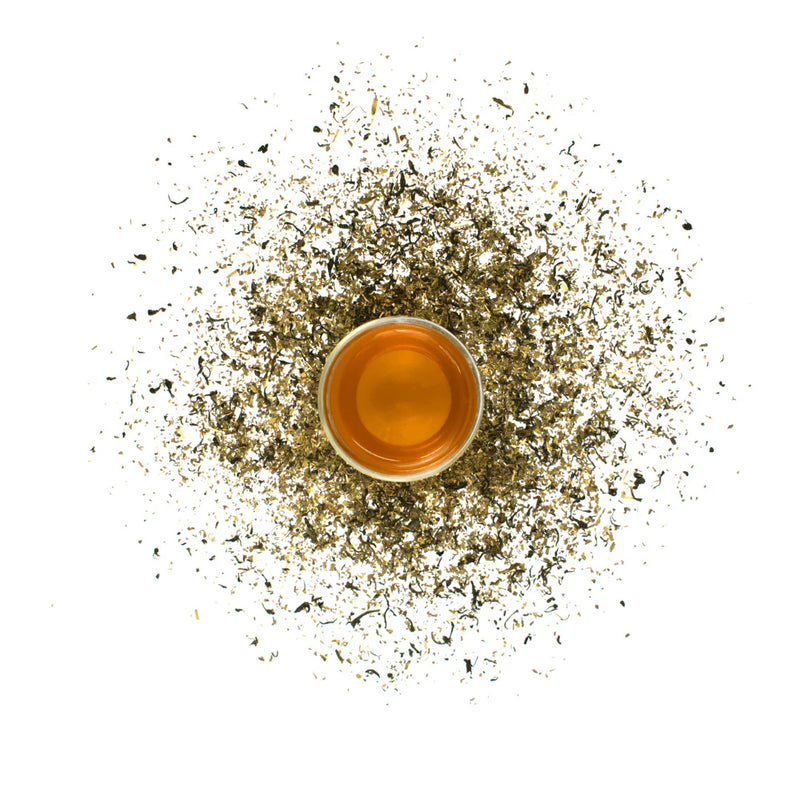 Tea cup surrounded by tea leaves on a white background