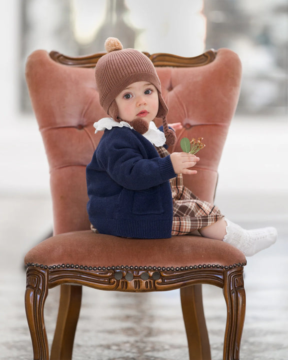 Child sitting on a decorative chair holding a small plant - Toshi Organic Cardigan Remy Ink
