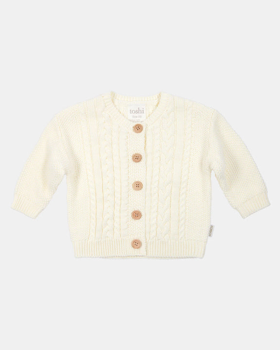 Cream-colored baby cardigan with buttons on a white background