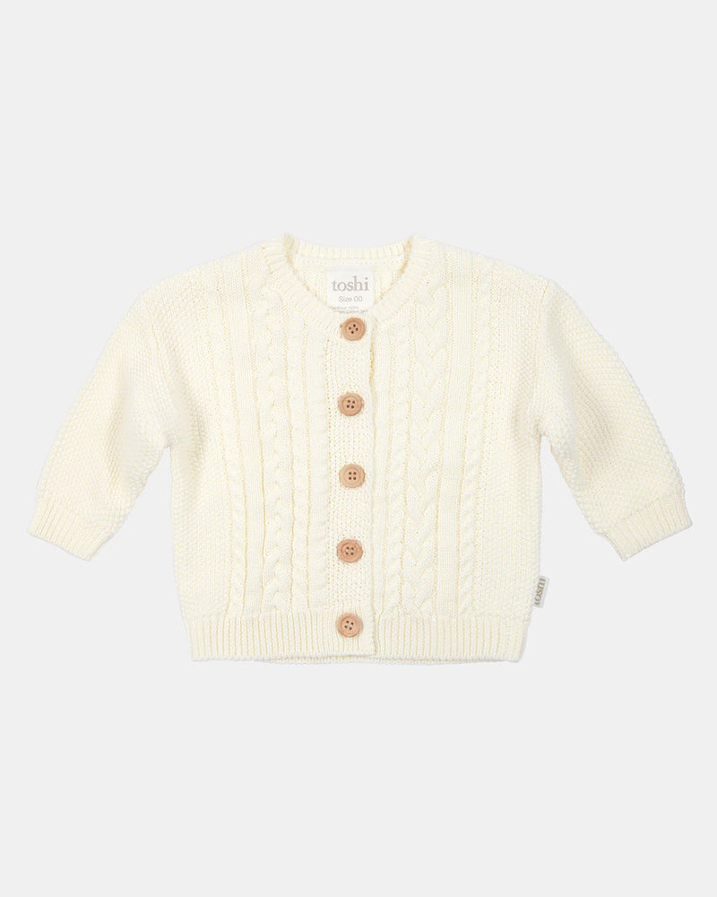 Cream-colored baby cardigan with buttons on a white background