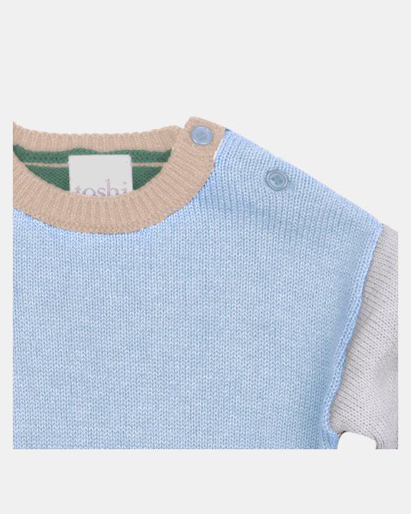 Close-up of a baby sweater with a visible brand label on a white background