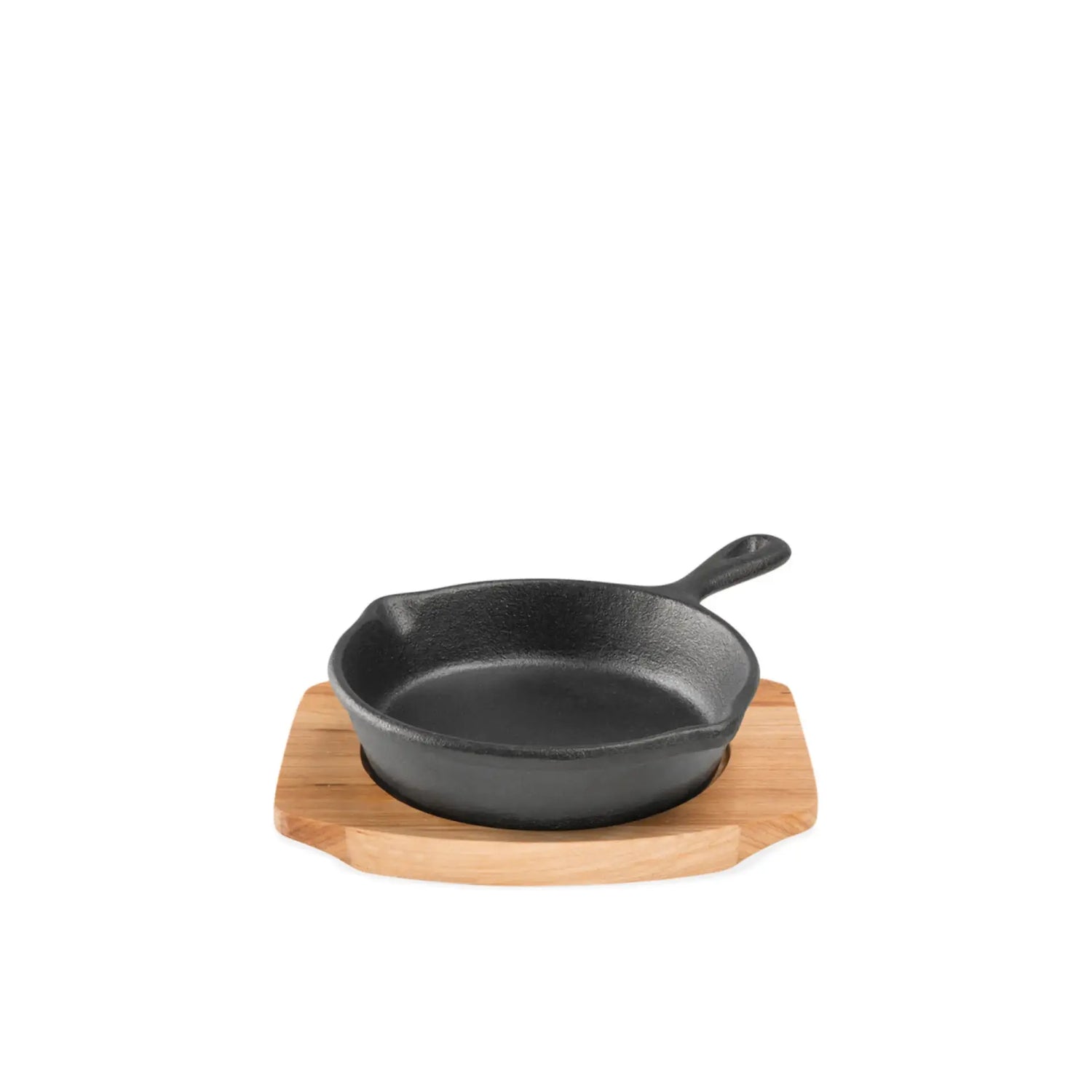 Black cast iron skillet on a wooden trivet against a white background