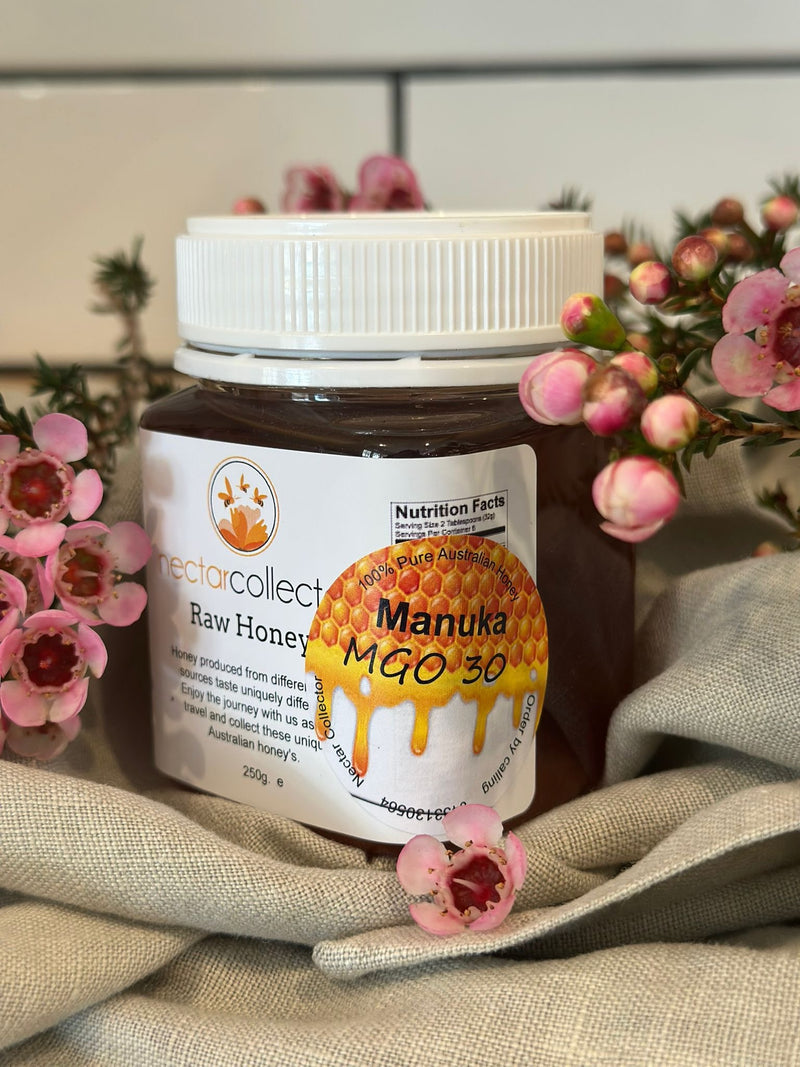 Jar of Manuka honey with flowers on a textured surface