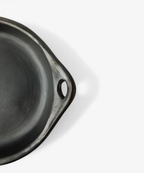 Handmade La Chamba round cookware dish crafted from dark clay with artisan finish.