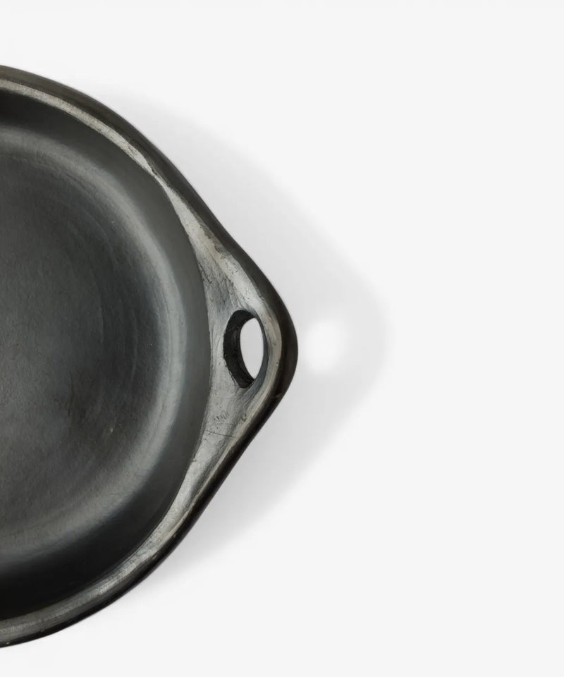 Handmade La Chamba round cookware dish crafted from dark clay with artisan finish.