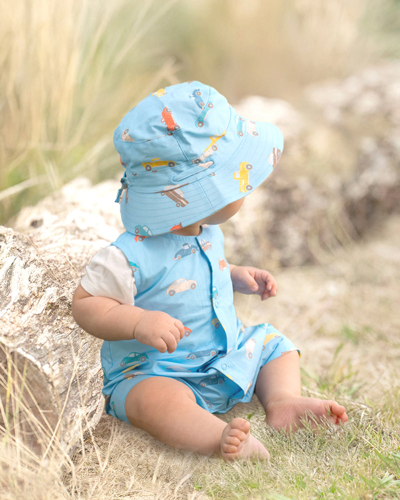 Child wearing Toshi Sunhat Ryder Fast Lane Cyan with car-print design and chinstrap.