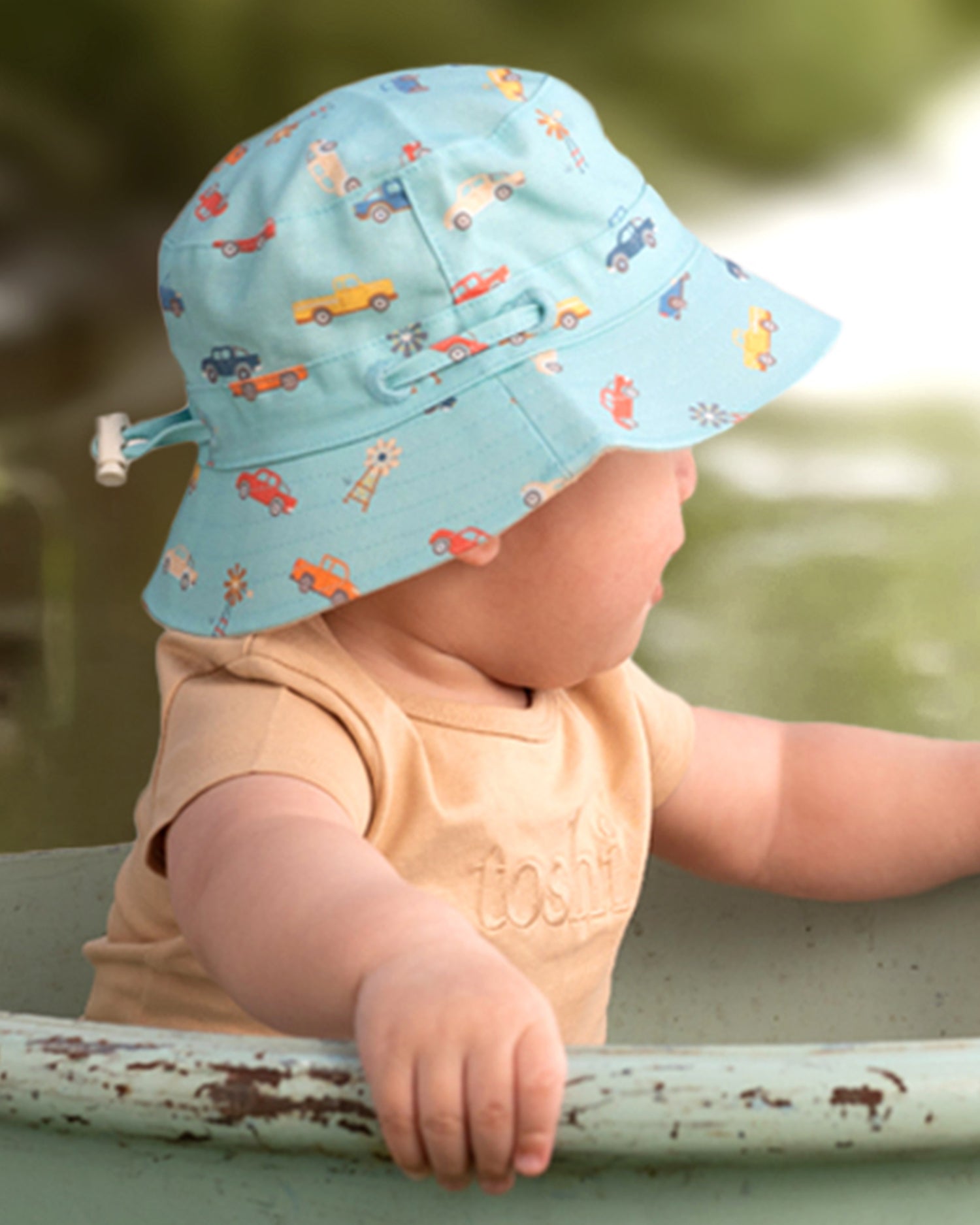 Child wearing Toshi Sunhat Ryder Utes Teal with adjustable chin strap.