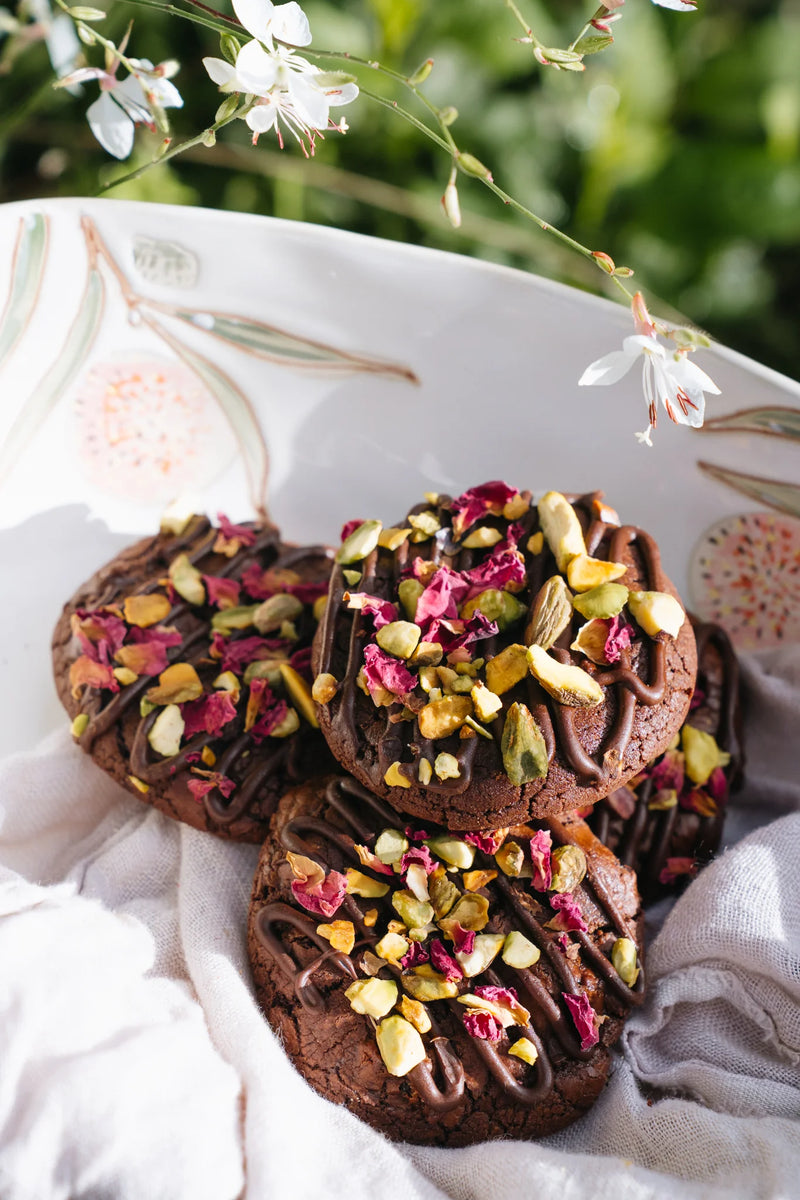 Chocolate cookies with dried flowers on a decorative plate with a floral background