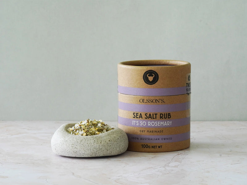 Ollsson's sea salt rub container with a small dish of salt on a light surface.