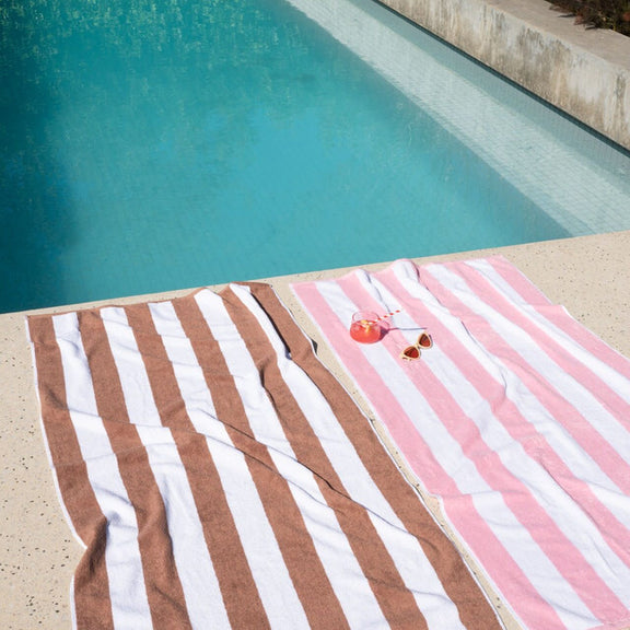 Pink beach towel styled by the water