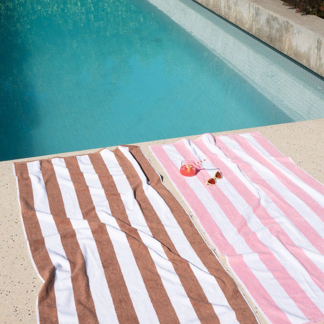 Pink beach towel styled by the water