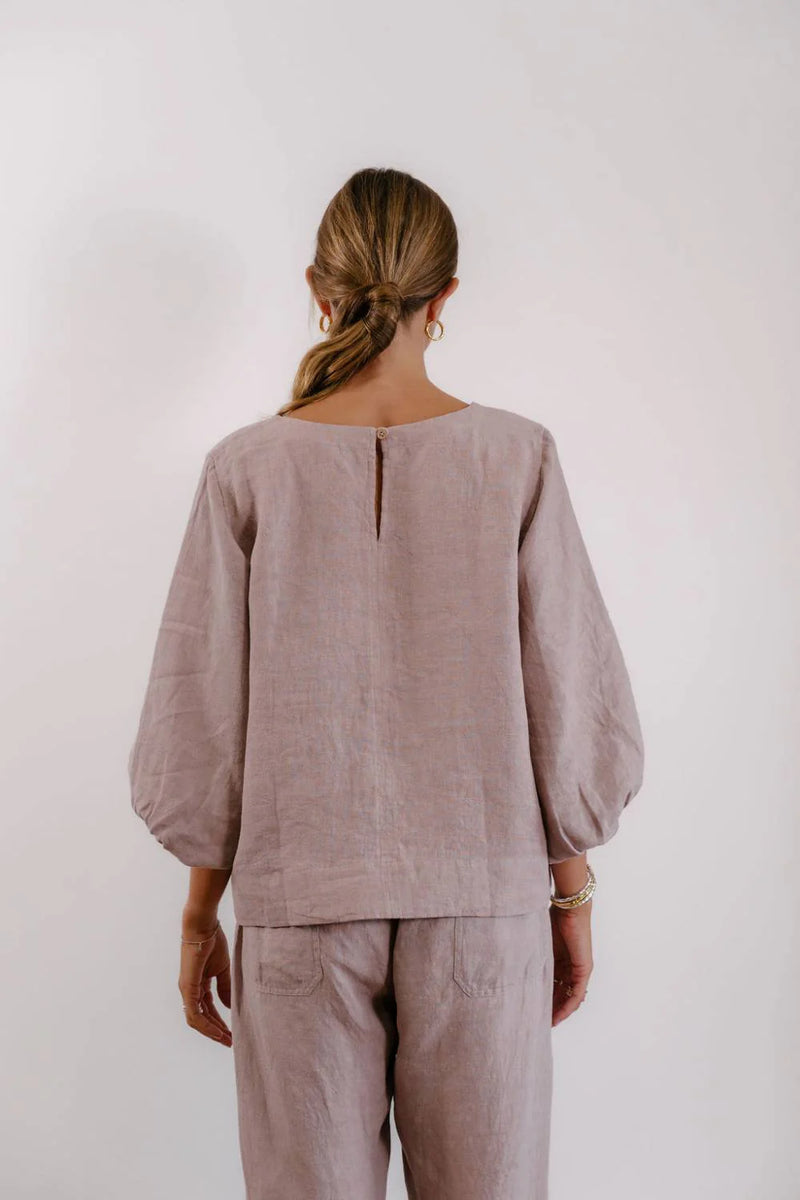 Women's lilac linen blouse with front stitch detail, round neckline and natural wooden button closure.