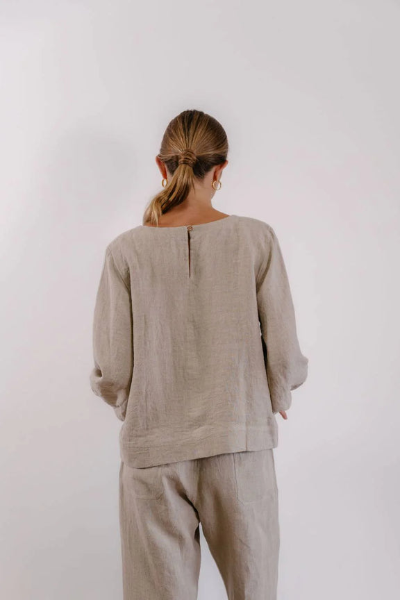 Women's natural linen blouse featuring front stitch detail, round neckline and wooden button closure.