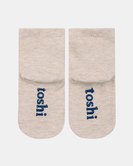 Pair of beige socks with 'toshi' branding on a white background