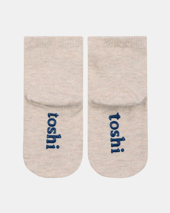 Pair of beige socks with 'toshi' branding on a white background