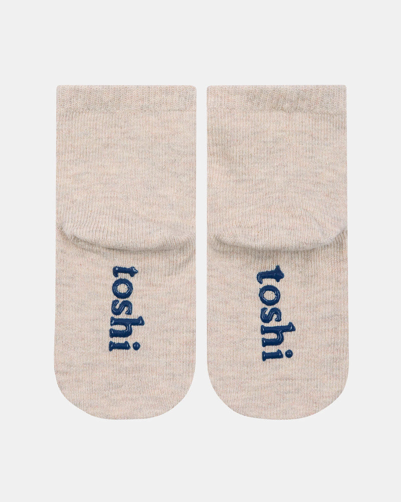 Pair of beige socks with 'toshi' branding on a white background