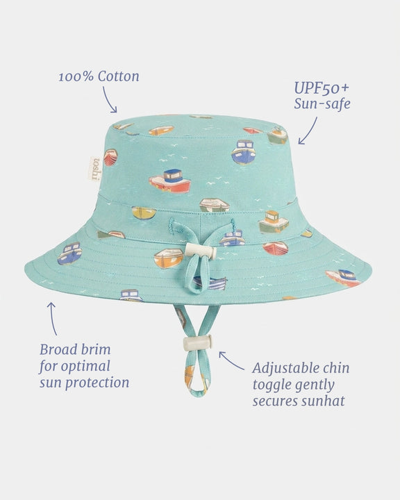 A light blue bucket sun hat with a colorful boat pattern, shown with feature callout text and arrows on a light gray background.
