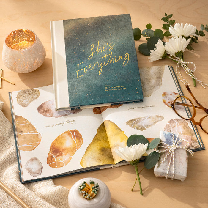 Open book titled 'She's Everything' on a wooden surface with decorative items.