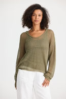 Woman wearing a green sweater and white pants on a white background